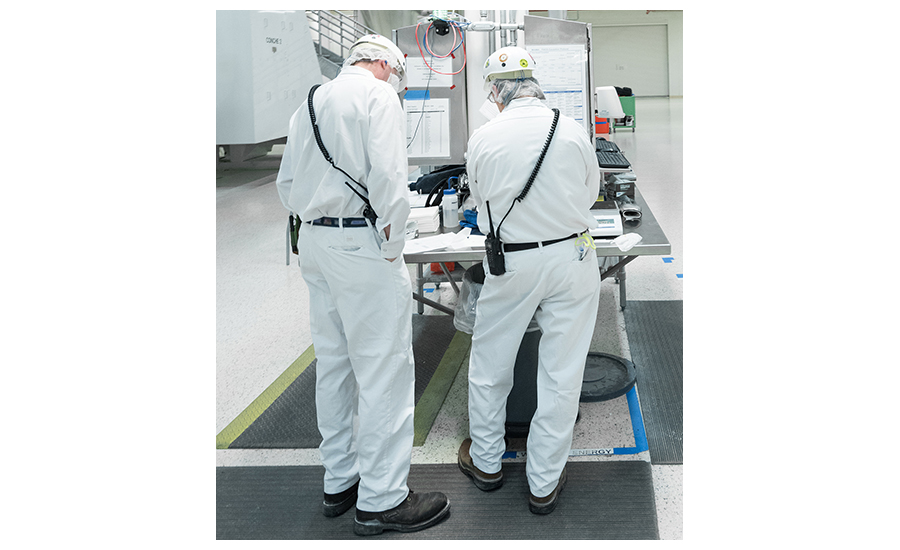 Image of two factory workers wearing proper safety attire for company-owned two-way radios