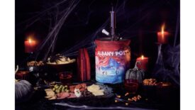 Angry Orchard's Halloween mini keg surrounded by a charcuterie board, a candle, and a spooky dark background