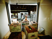 Man Loading Produce Boxes into Back of Truck